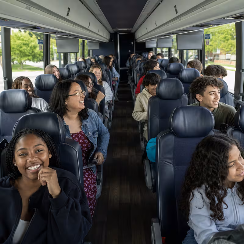 Group boarding a white charter bus for School Transportation transportation in Springfield